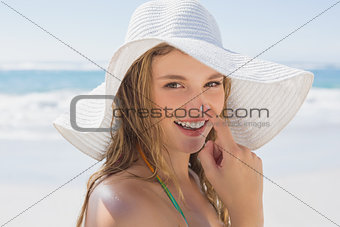 Beautiful girl putting spf on nose on the beach smiling at camera