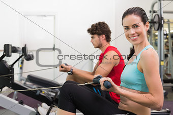 Smiling brunette working out on the rowing machine