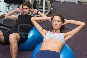 Fit man and woman doing sit ups on exercise ball