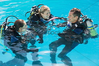 Smiling friends on scuba training in swimming pool