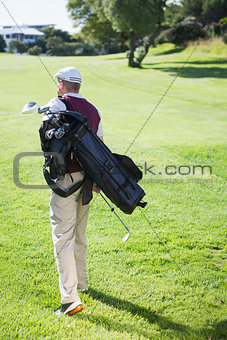 Golf player carrying his bag and walking