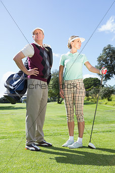 Golfing couple standing and looking around