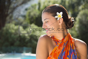 Brunette in sarong smiling by the pool