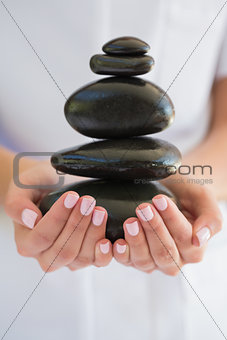 Beauty therapist holding pile of stones for massage