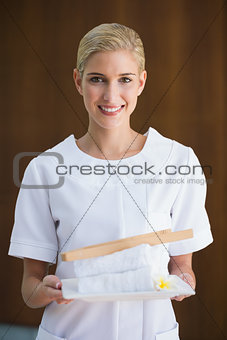 Smiling beauty therapist holding white towels