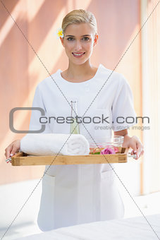Smiling beauty therapist holding tray of beauty treatments