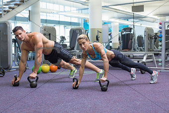 Bodybuilding man and woman lifting kettlebells in plank position
