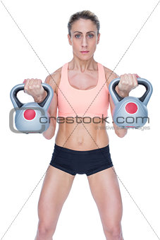 Serious female crossfitter lifting kettlebells