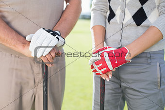 Golfing couple standing and holding clubs