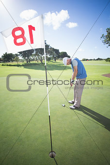 Golfer putting ball on the green at the eighteenth hole