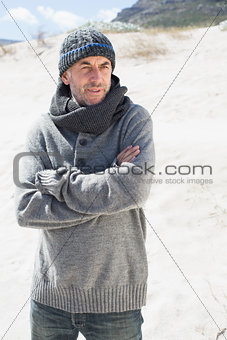 Attractive man shivering on the beach in hat and scarf