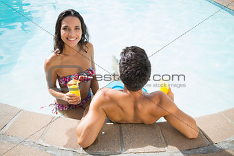 Attractive couple drinking cocktails in the pool