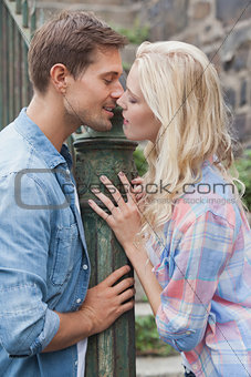 Hip young couple about to kiss by railings