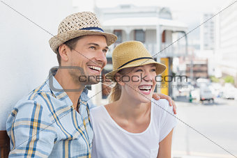 Young hip couple sitting on bench smiling