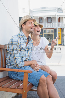Young hip couple sitting on bench smiling