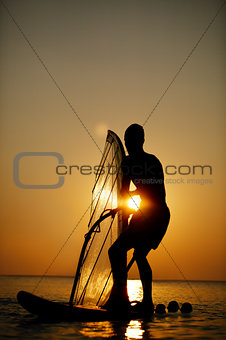 Man sailboarding at sunset