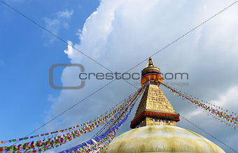 stupa with buddha eyes and prayer flags on clear blue sky