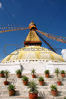 Stupa with buddha eyes and prayer flags on clear blue sky