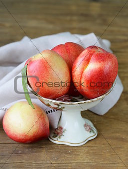 ripe fresh pink peaches in vase on a wooden table