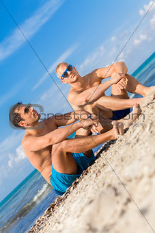 Two handsome young men chatting on a beach