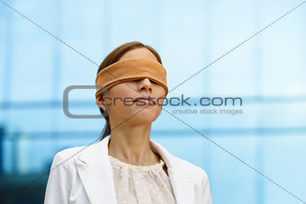 Blindfolded hispanic business woman near office building