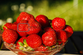 Bowl with fresh strawberries at green background