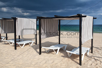 Different parasols and sun loungers on the empty beach on Tavira