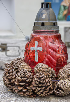 Red candle and pine cones on a marble grave in Brasov