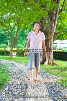asian older woman walking on the stone walkway