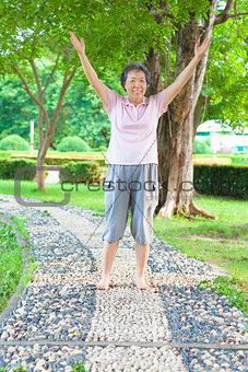 happy grandmother standing on stone walkway and raise hands