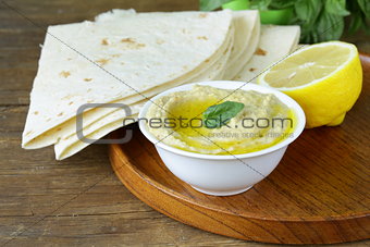 traditional hummus dip of chickpea with pita bread on a wooden table