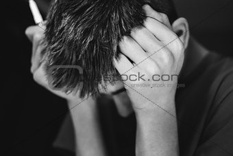 Teenage boy leaning his head against his fists