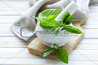 fresh green basil leaves in a marble mortar