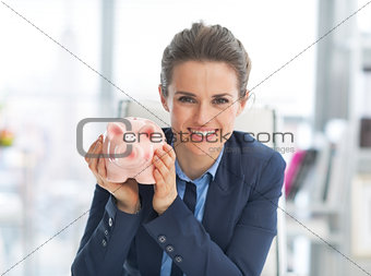 Portrait of happy business woman showing piggy bank
