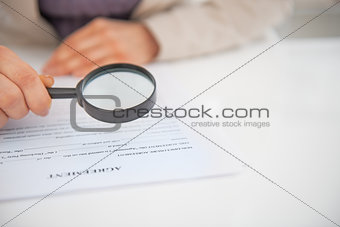 Closeup on business woman exploring document with magnifying len