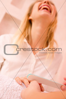 Manicurist filling fingernail with nail file