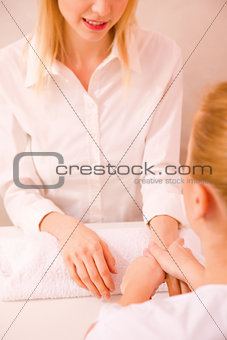 Masseuse massaging young woman's hand