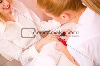 Beautician applying nail varnish to woman
