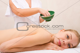Woman lying massage table in front of masseuse