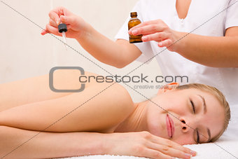 Therapist putting essential oil woman's back