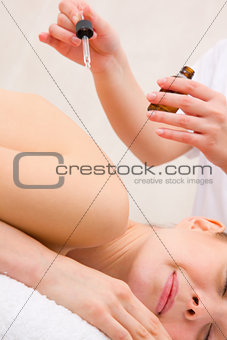 Masseuse pouring massage oil woman's back