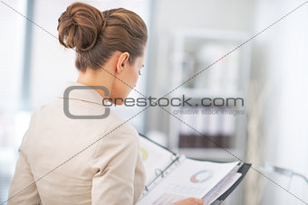 Business woman examining documents in office. rear view