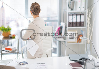 Business woman standing with document in office. rear view