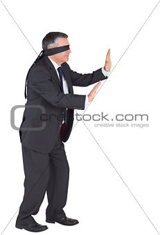 Mature businessman walking with blindfold