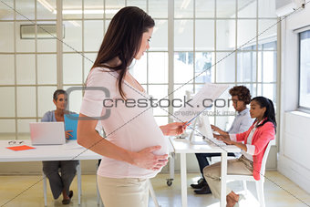 Pregnant worker touches belly and looks at file