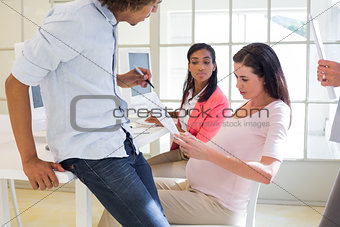 Casual pregnant businesswoman working with colleagues