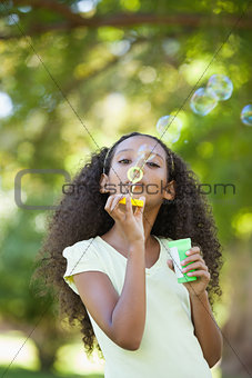Young girl blowing bubbles in the park