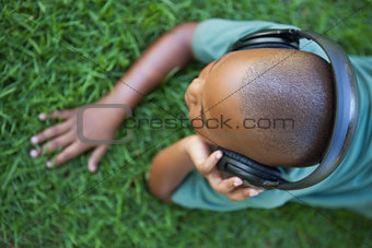 Little boy lying on grass listening to music