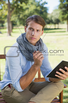 Stylish young man holding notepad and thinking