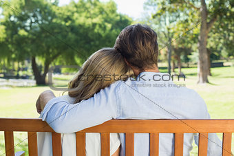 Affectionate couple relaxing on park bench together